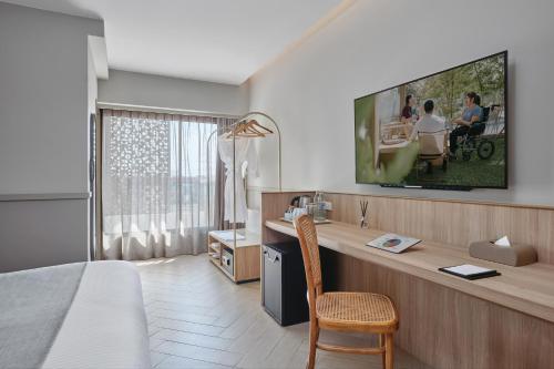 a hotel room with a bed and a desk and a tv at Somerset Sukhumvit 71 Bangkok in Bangkok