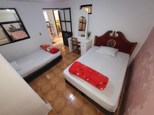 ein kleines Zimmer mit 2 Betten und einem roten Kissen in der Unterkunft Dpto Cómodo Barrio Guadalupe Céntrico con Estac y FREE WIFI in San Cristóbal de las Casas