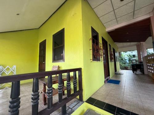 a yellow building with a porch and a balcony at Sawasdee House in Lamai