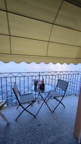 a table and chairs on a balcony with the ocean at On the Lake in Bellano