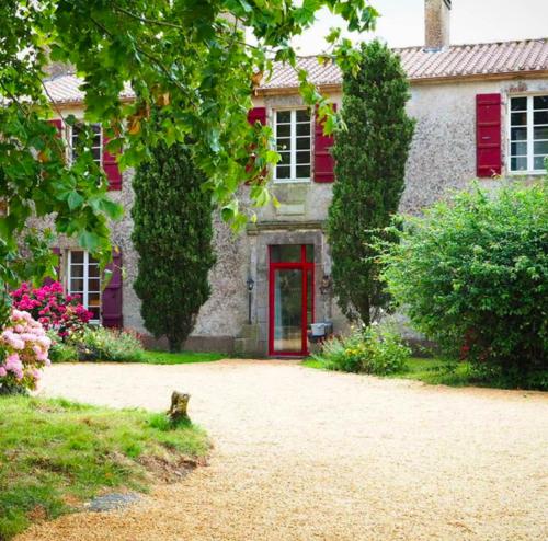 a house with a red door and a cat in the driveway at Jolly Château - Family and Friends suite in Le Bernard