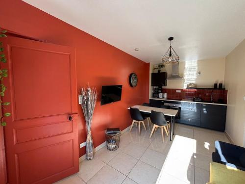 a kitchen and dining room with a red wall at Les Hulottes - Sur la route du Mont-St-Michel in Céaux