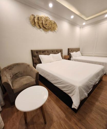 a bedroom with two beds and a chair and a table at BREAKING DAWN- TAEYANG Hotel Phú Quốc in Phu Quoc