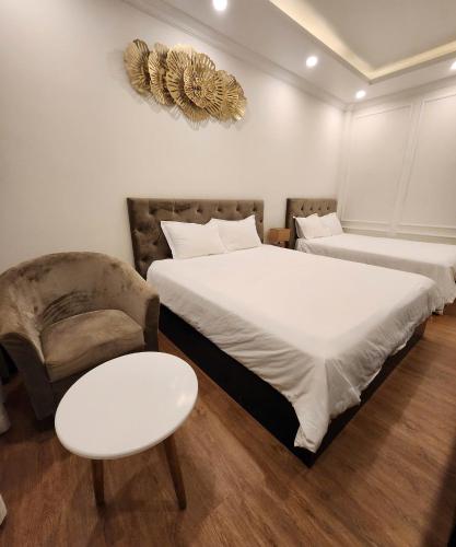 a bedroom with two beds and a chair and a table at BREAKING DAWN- TAEYANG Hotel Phú Quốc in Phu Quoc