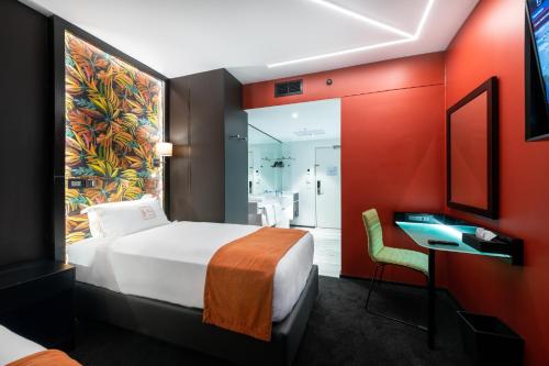 a hotel room with a bed and a desk and a bathroom at Hotel Sky Sandton in Johannesburg