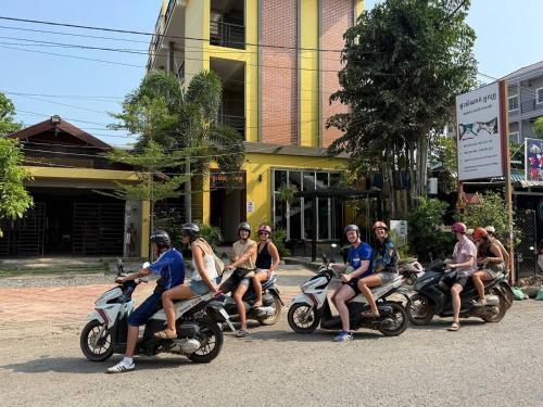 a group of people riding motorcycles down a street at Neakru Guesthouse and Restaurant in Kampot