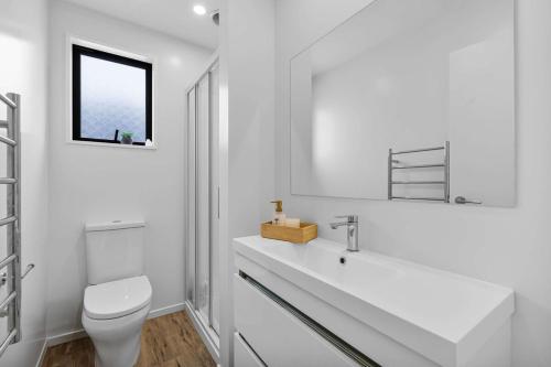 a white bathroom with a toilet and a sink at Charming 2-Bedroom Townhouse in Christchurch