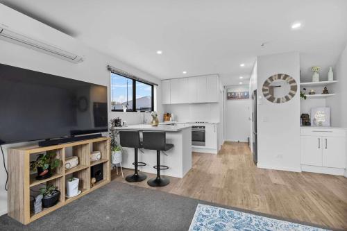 a kitchen with white cabinets and a large television at Charming 2-Bedroom Townhouse in Christchurch