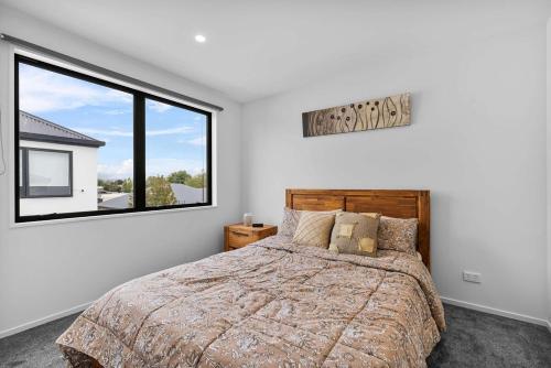 a bedroom with a bed and a large window at Charming 2-Bedroom Townhouse in Christchurch