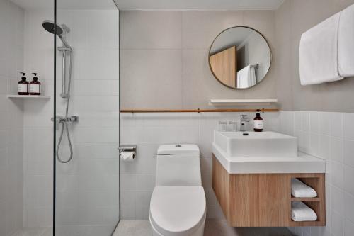 a bathroom with a toilet and a sink and a mirror at Somerset Sukhumvit 71 Bangkok in Bangkok