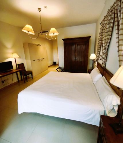 a bedroom with a large white bed and a desk at Hotel VillaMarcilla in Marcilla