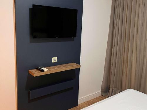 a bedroom with a tv on a blue wall at ibis Styles Confins Aeroporto in Lagoa Santa