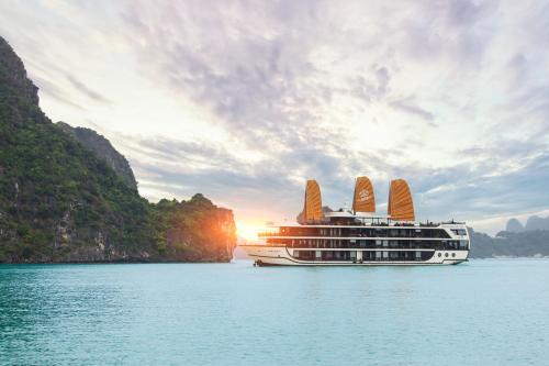 a cruise ship in the water at sunset at La Regina Legend Cruise in Ha Long