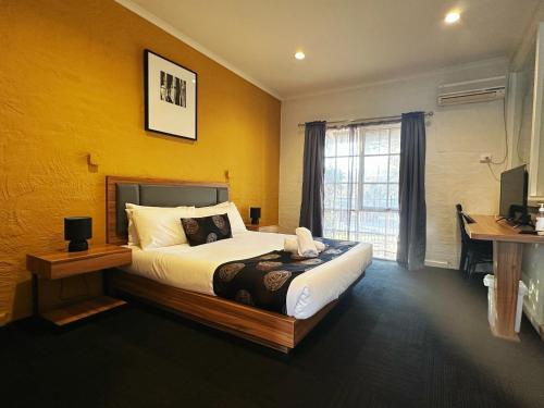 a bedroom with a bed and a desk and a window at Greensborough Motel in Melbourne