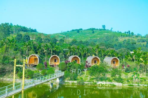 a group of huts on a hill next to a river at HDT Farm Stay Thanh Chuong in Thái Nhã
