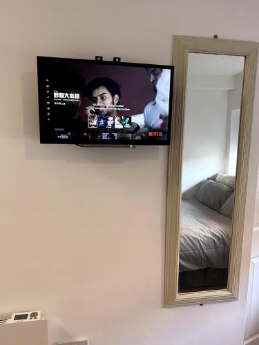 a flat screen tv on a wall next to a mirror at Smart Studio in Milton Keynes - Workspace in Woolstone