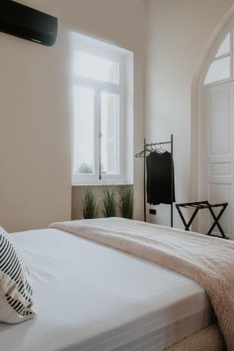 a white bedroom with a large white bed with a window at The Hub Syros in Ermoupoli