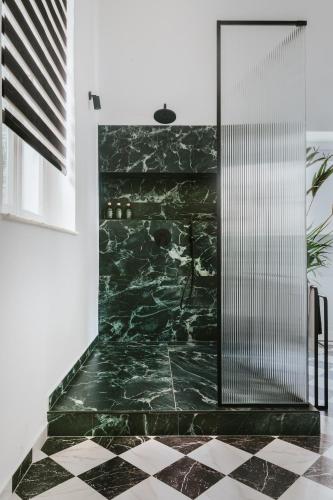 a glass shower in a bathroom with a black marble floor at The Hub Syros in Ermoupoli