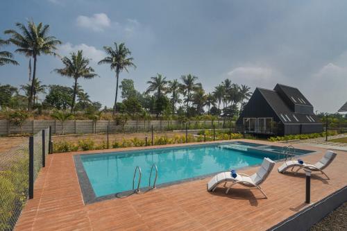 a swimming pool with two chairs and a house at Palasa by Aer Studio in Nashik