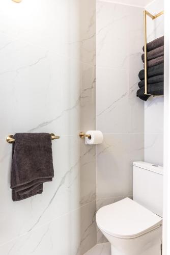 La salle de bains blanche est pourvue de toilettes et d'une serviette. dans l'établissement Studio élégant esprit Loft avec AC, à Paris