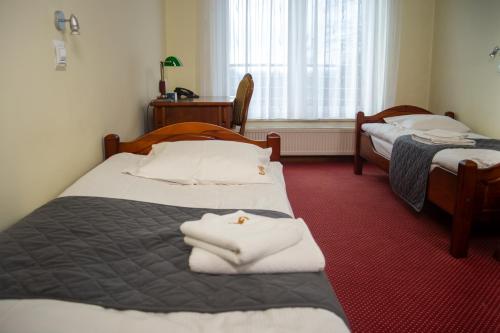 two beds in a hotel room with towels on them at Dom rekolekcyjny Vincentinum in Krzeszowice