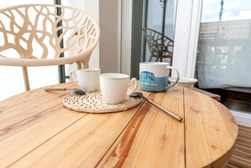 - une table en bois avec deux tasses à café dans l'établissement Le Logis du Bassin - Meublé 3 étoiles, à Arcachon