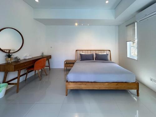 Un dormitorio con una cama, un escritorio y un espejo. en Vila Pantai Sanur, en Sanur