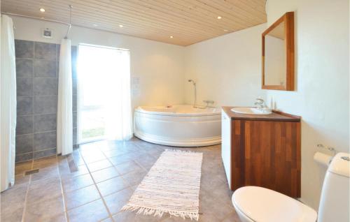 a bathroom with a tub and a toilet and a sink at Holiday Home Glombak in Øsløs
