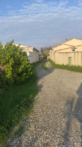 a gravel road next to a fence and a building at Au Petit Luberon in Cheval-Blanc