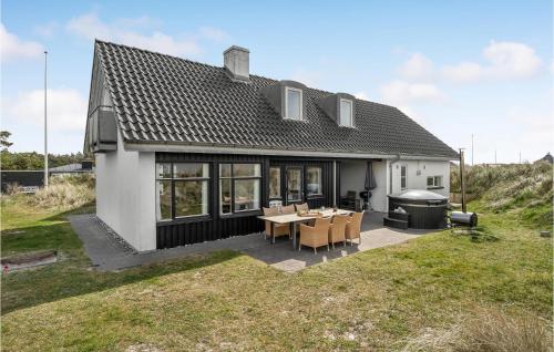 a house with a table and chairs and a grill at Holiday Home Plantagevej Ringkøbing Xii in Søndervig