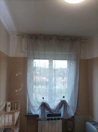 a window with a white curtain in a bathroom at La Sosta in Lunigiana in Monti di Licciana Nardi