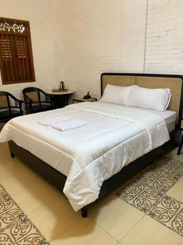 a bed with white sheets and pillows on it at The Satu Stay Damai in Kejayan