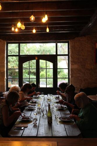 Un groupe de personnes assises autour d'une longue table en bois dans l'établissement A Cozy Accessible Cottage with a Private Garden Le Mas No 16, à Ayen