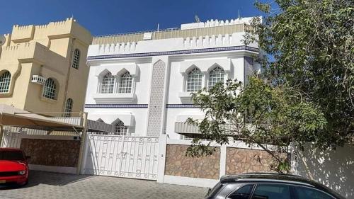 una casa blanca con un coche rojo estacionado frente a ella en room, en Mascate