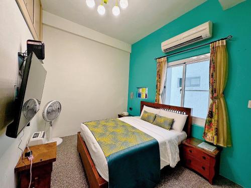 a bedroom with a bed and a blue wall at Village Hostel in Xiaoliuqiu