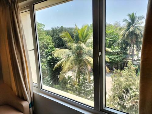 a window with a view of a palm tree at Zip By Spree Hotels Surabi International Vellore in Vellore