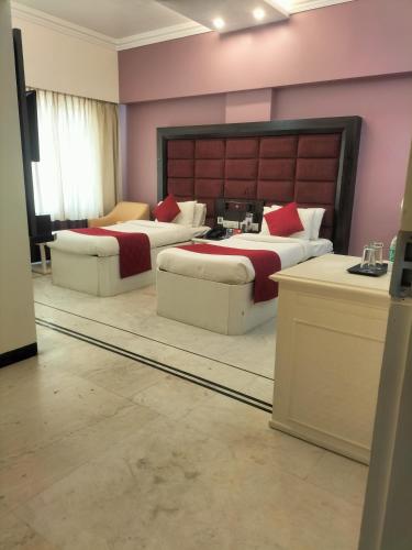 two beds in a room with pink walls at Zip By Spree Hotels Surabi International Vellore in Vellore