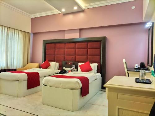 two beds in a room with a pink wall at Zip By Spree Hotels Surabi International Vellore in Vellore