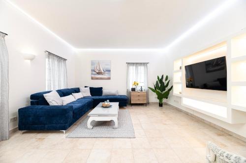 a living room with a blue couch and a tv at Villa Irene Royale - Pool - Sea View - Free Cruise in Tigaki