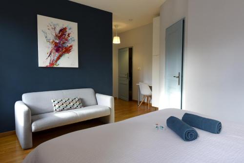 a bedroom with a white bed and a couch at Chambres d'hotes au Domaine de Clarat in Lafarre