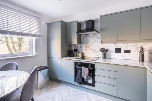 a kitchen with white appliances and a table and a window at Modern Comfort in Old Aberdeen in Aberdeen