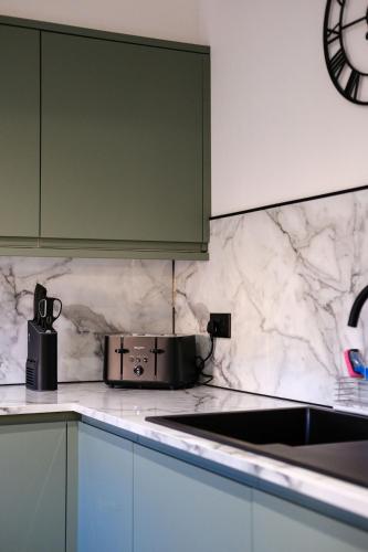 a kitchen with green cabinets and a counter top at Modern Comfort in Old Aberdeen in Aberdeen