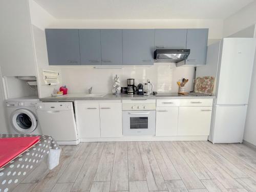 une cuisine avec des appareils électroménagers blancs et des armoires bleues dans l'établissement F2 avec terrasse et parking privé à Fréjus, à Fréjus