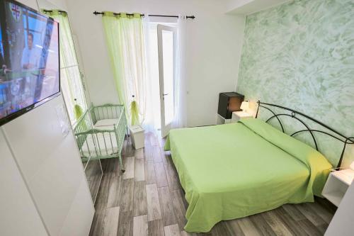 een slaapkamer met een groen bed en een flatscreen-tv bij Il Gelso di Sofia B&B in Tortoreto Lido