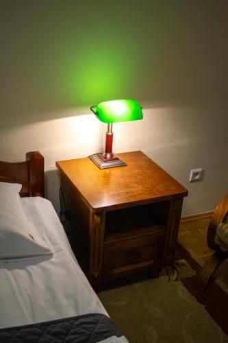 a green lamp on a wooden table next to a bed at Dom rekolekcyjny Vincentinum in Krzeszowice