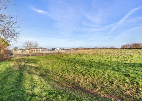 a field of green grass with a house in the background at Bay Retreat Villas in Saint Merryn