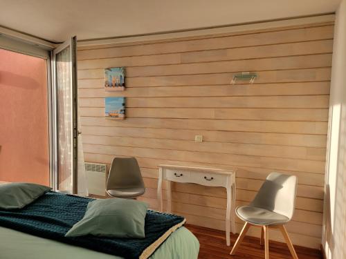 - une chambre avec deux chaises, un lit et un bureau dans l'établissement Beau T3 au calme, vue mer imprenable, à Sète