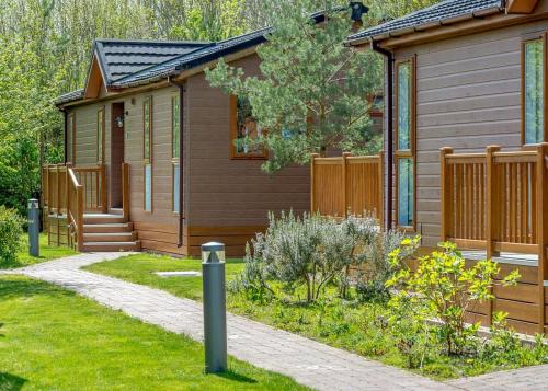 a small house with a fence next to a garden at Canterbury Reach Lodge Retreat in Kent