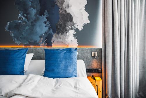 a bedroom with a bed with blue pillows and a painting at Comfort Hotel Sello in Espoo