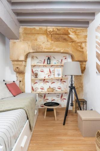 une chambre avec un lit et un mur en pierre dans l'établissement Petit studio au coeur de Caen, à Caen